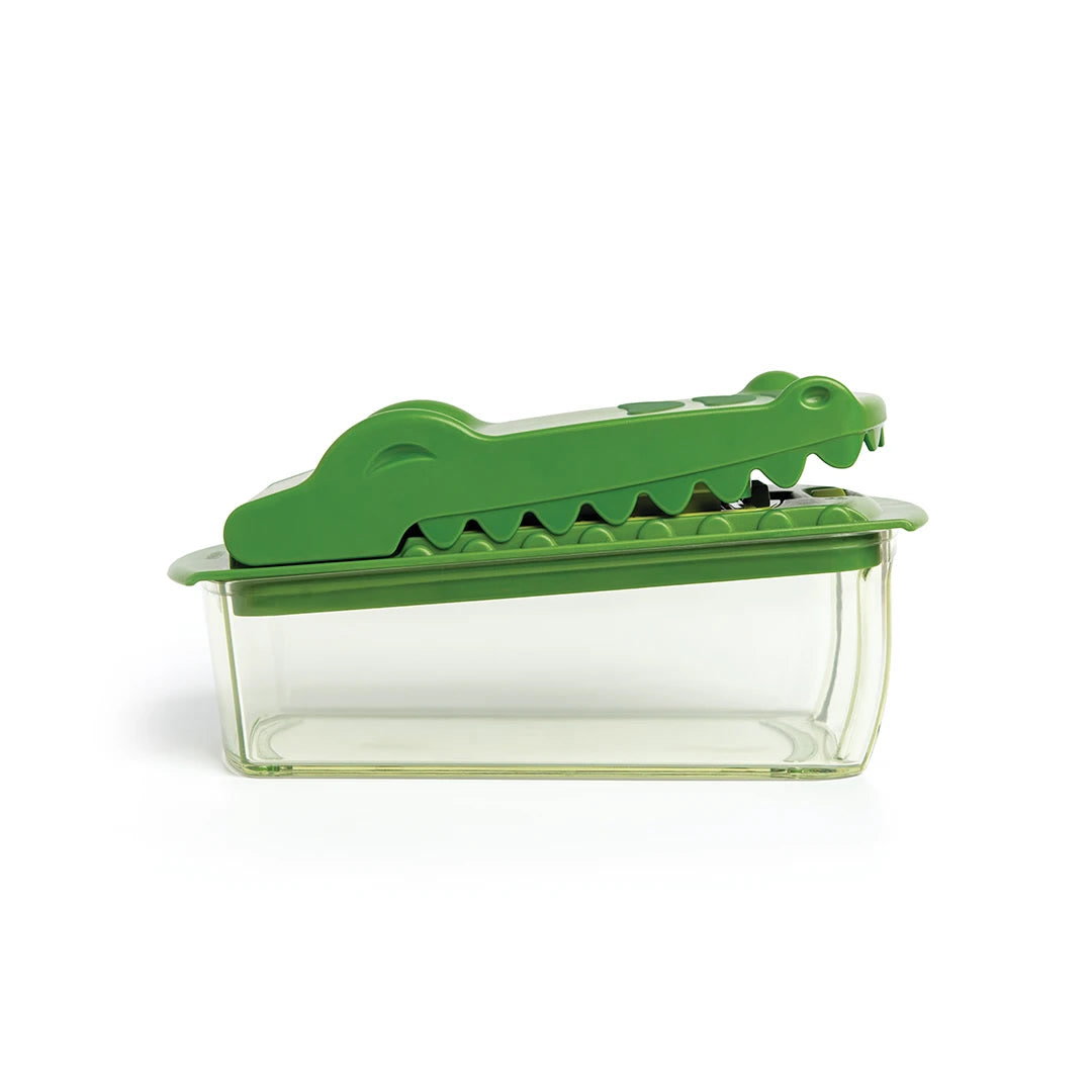 OTOTO Croc Chop green crocodile vegetable chopper mid-bite on a red onion