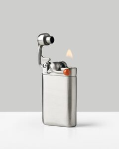 Craighill Swingtop pocket lighter in stainless steel with its top swung open and a flame burning