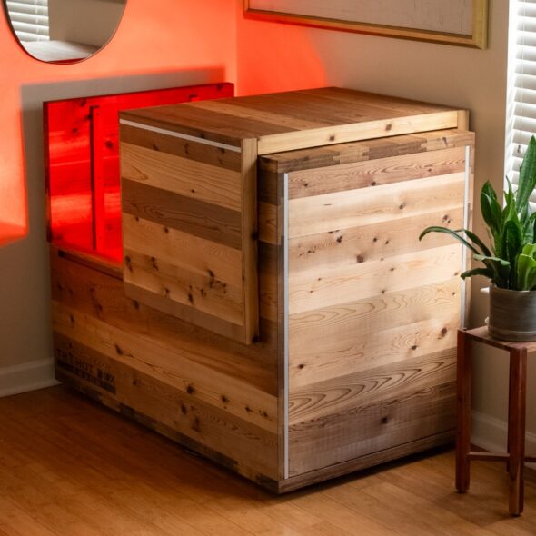 The Hot Box Sauna cedar box sauna glowing red in a living room corner