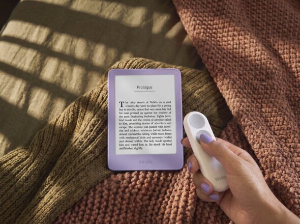 Person reading a Kindle in bed while holding the Kindle Click Bluetooth page-turn remote