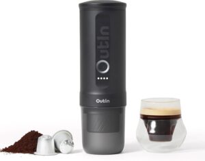OutIn Nano 2 portable espresso machine in Space Gray next to a glass of espresso