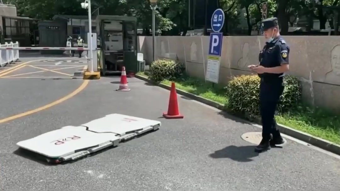 Thin folding car-moving robot lying open on the pavement next to a security guard