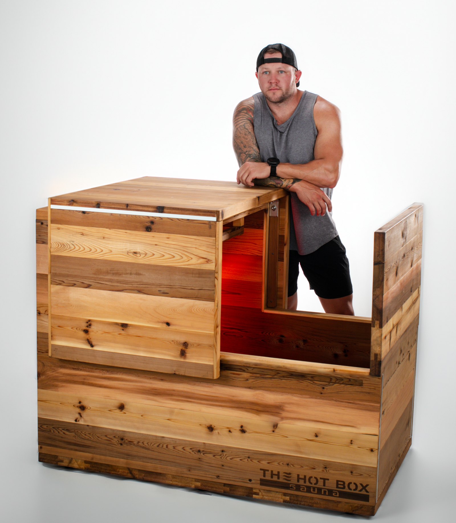 Man leaning on The Hot Box Sauna with its sliding cedar lid pulled open