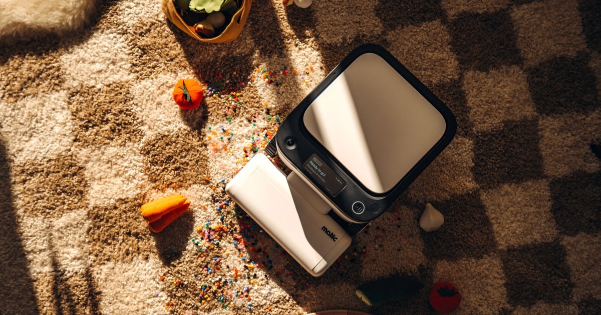 Matic robot vacuum cleaning a checkered rug around scattered toys