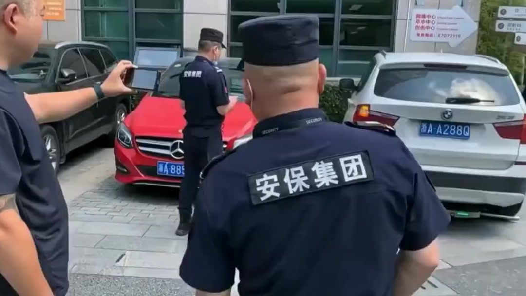 Security guard steering the car-moving robot with a phone while others watch