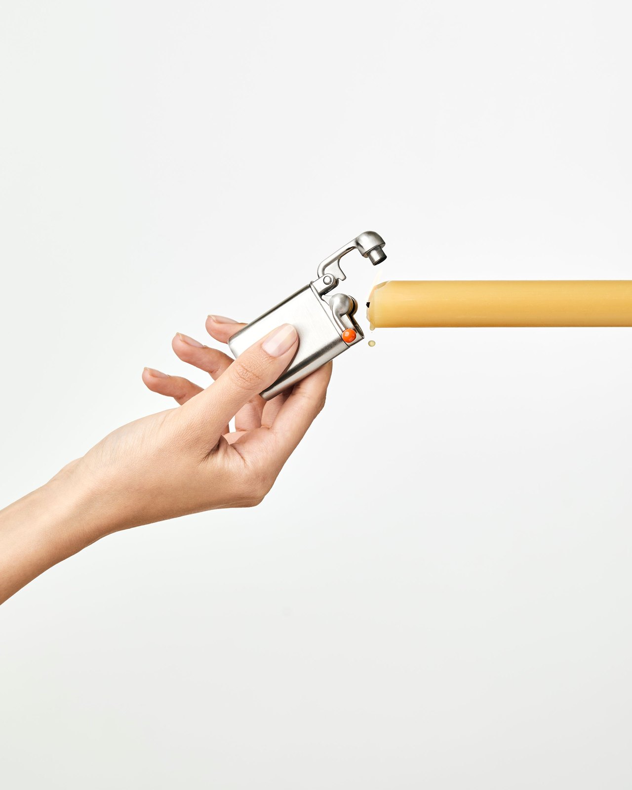 Hand using the stainless Craighill Swingtop lighter to light a taper candle