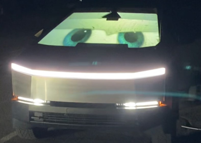 Cybertruck parked at night with giant cartoon eyes on a HoloGlass front windshield screen