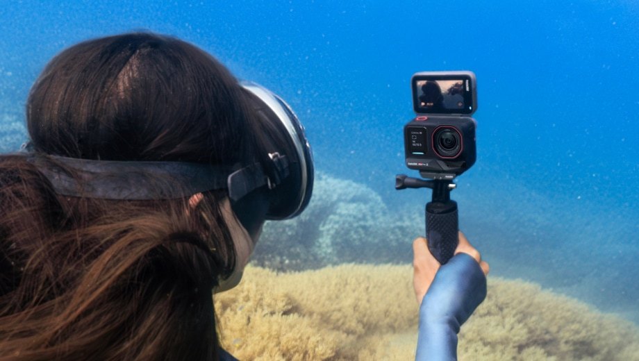 Snorkeler holding an Insta360 Ace Pro 2 on a grip underwater with the flip screen facing her for a selfie
