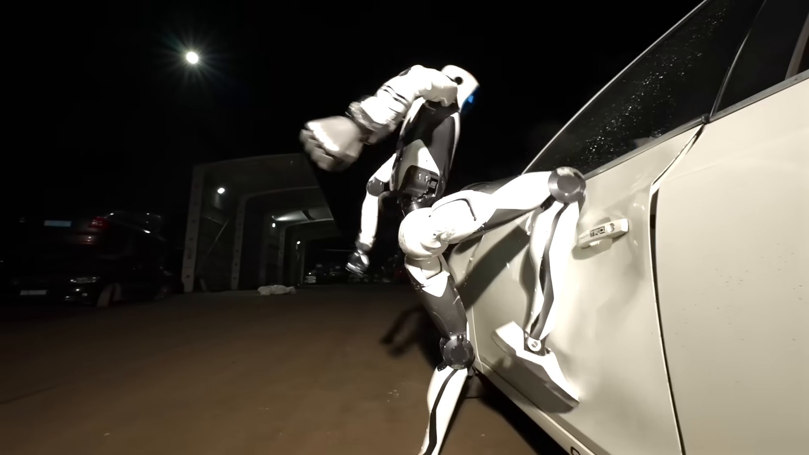 Unitree H2-X humanoid robot kicking the door of a white car at night
