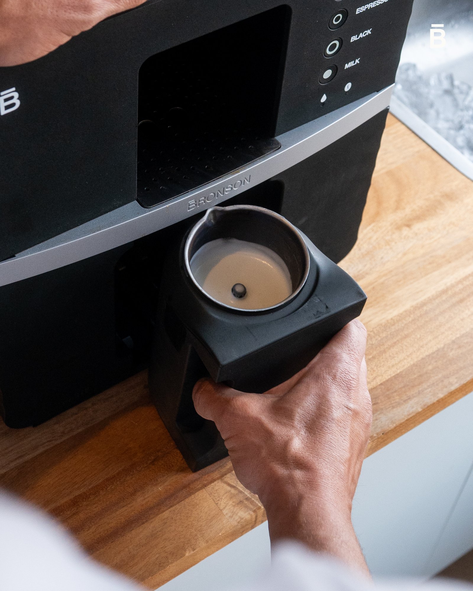 Hand lifting the Bronson built-in milk frother jug out of the machine