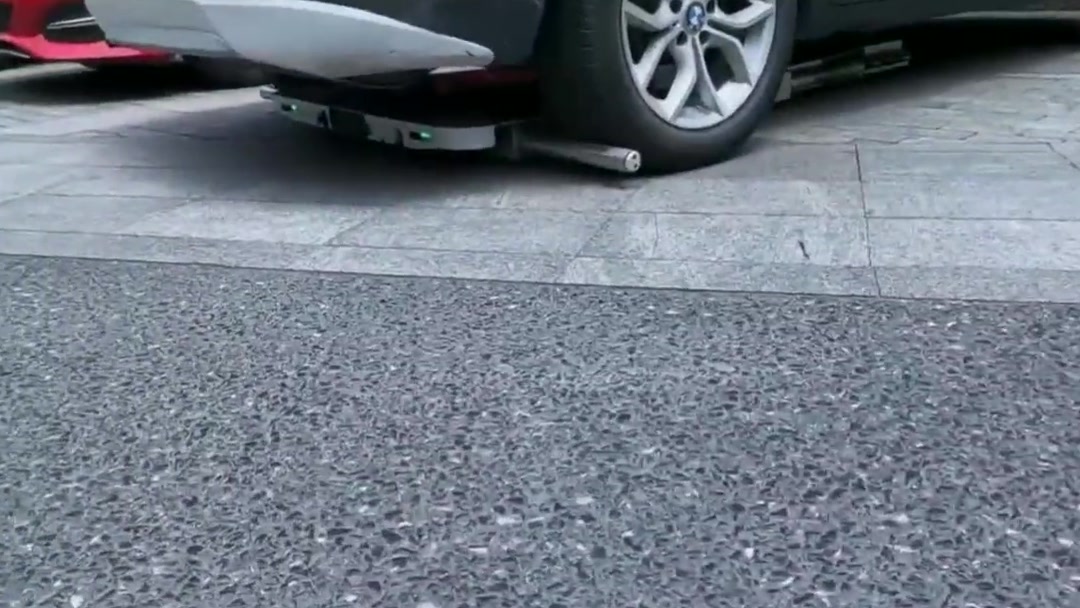 Close-up of the robot's wheel grippers clamped under a white SUV