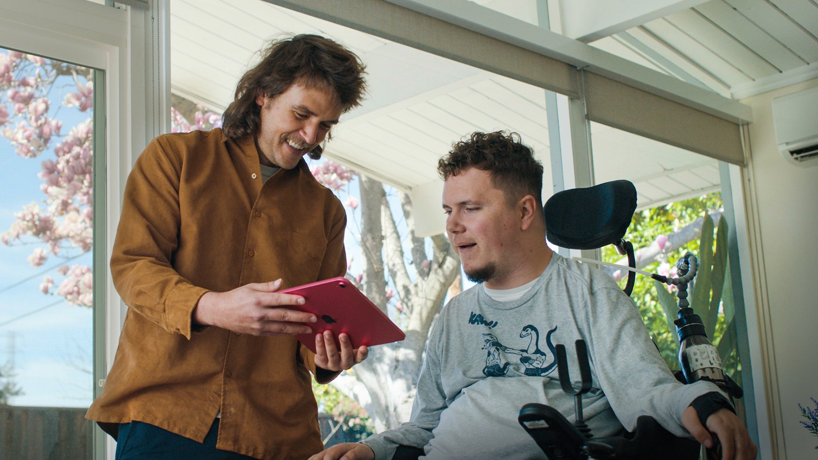 MouthPad user in a wheelchair working through a tablet with a helper