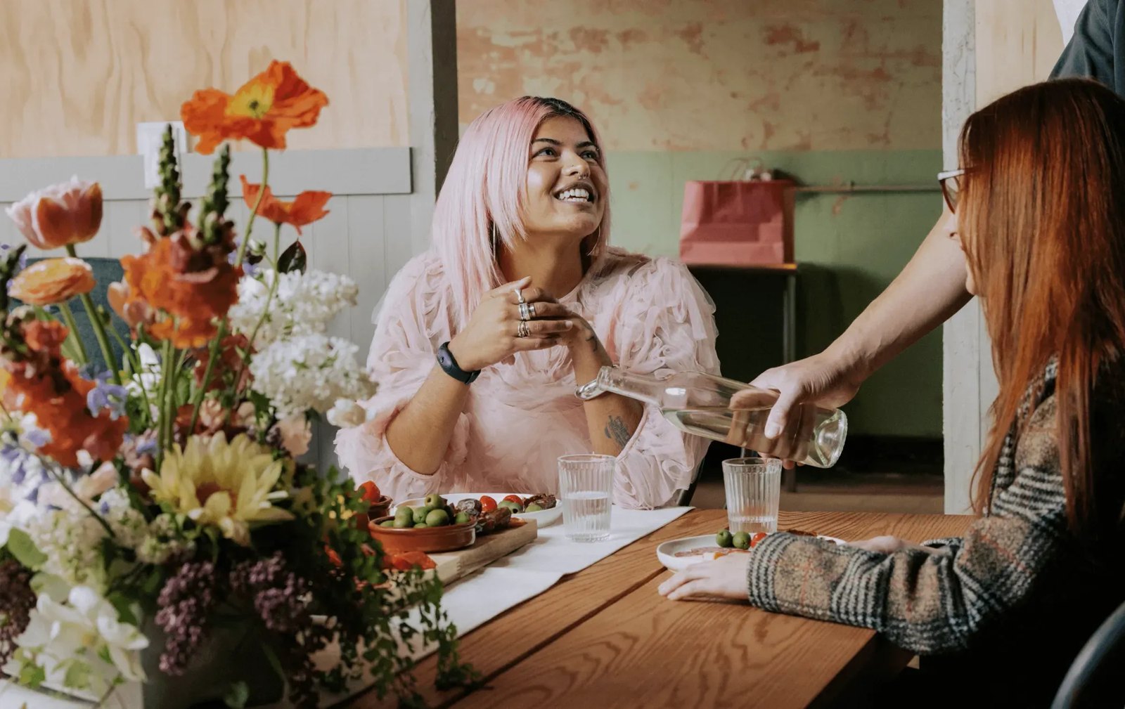 Friends talking around a dinner table with flowers, the kind of conversation Bee Frontier summarizes