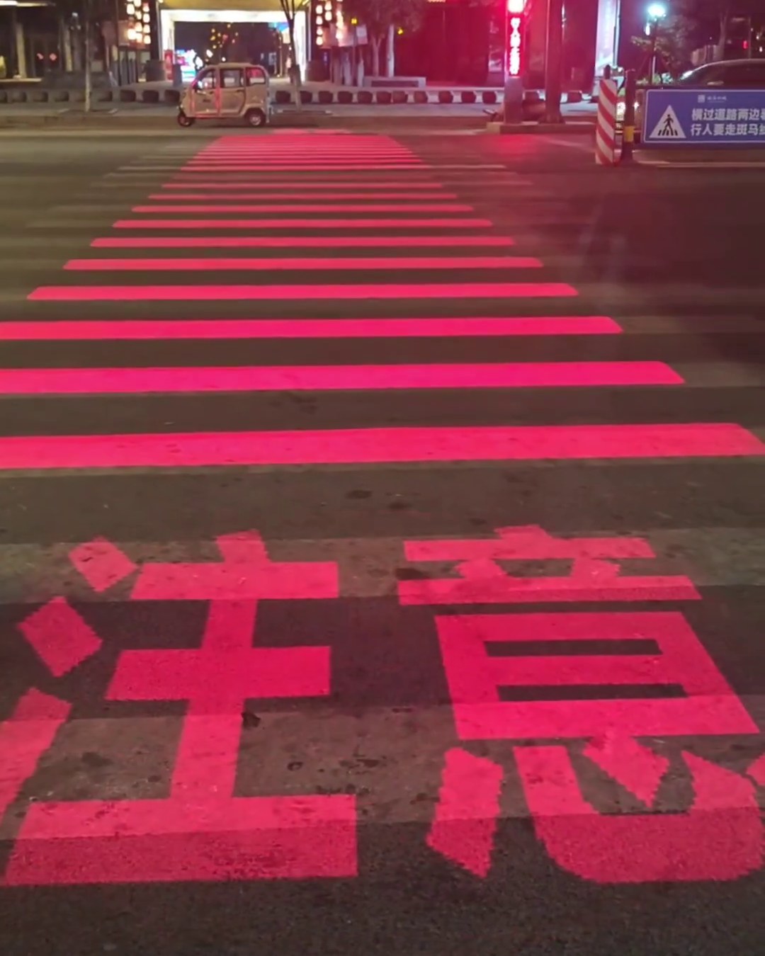 Red LED crosswalk showing a large Chinese caution warning on the road