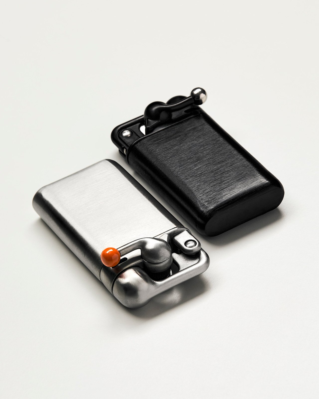 Craighill Swingtop lighters in stainless steel and black finishes lying side by side