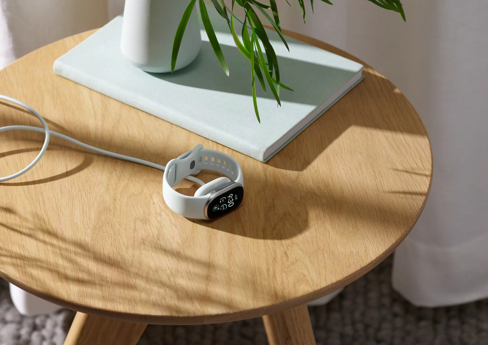 Fitbit Edge on its magnetic charger on a wooden side table