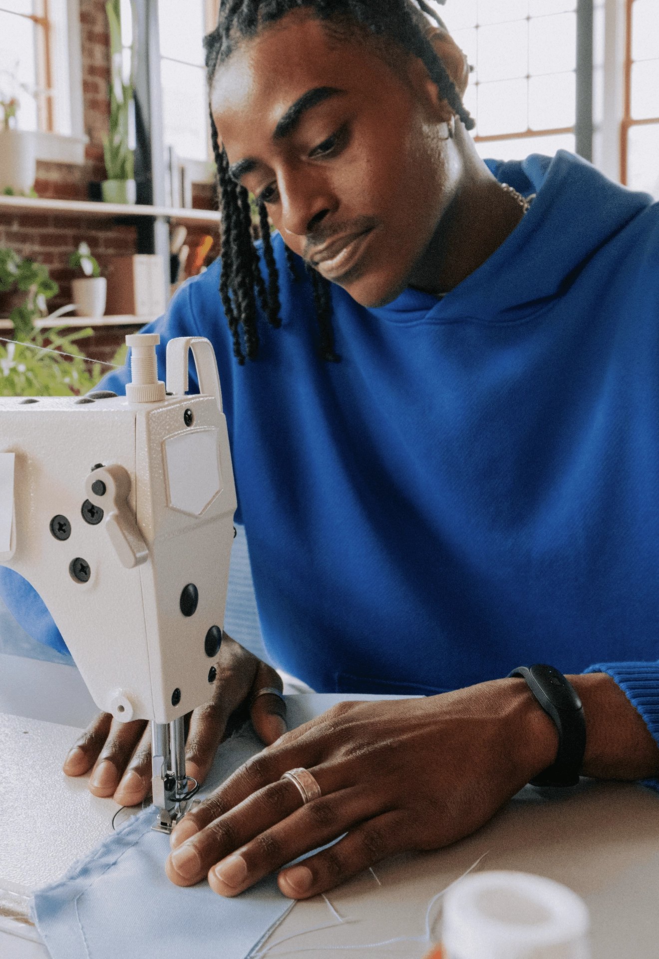 Man at a sewing machine wearing a black Bee Frontier on his wrist
