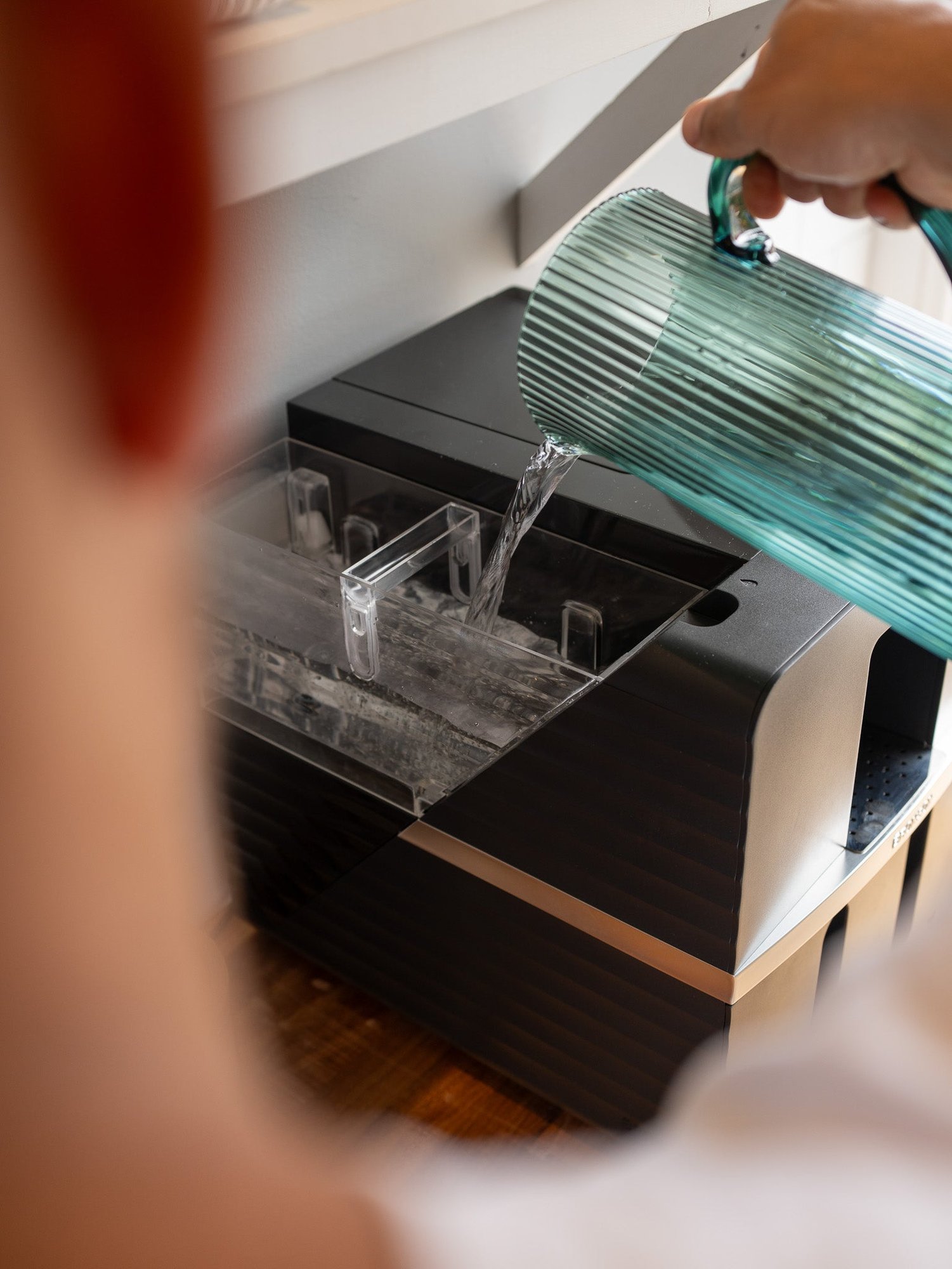 Pouring water into the Bronson coffee machine's tinted removable water tank