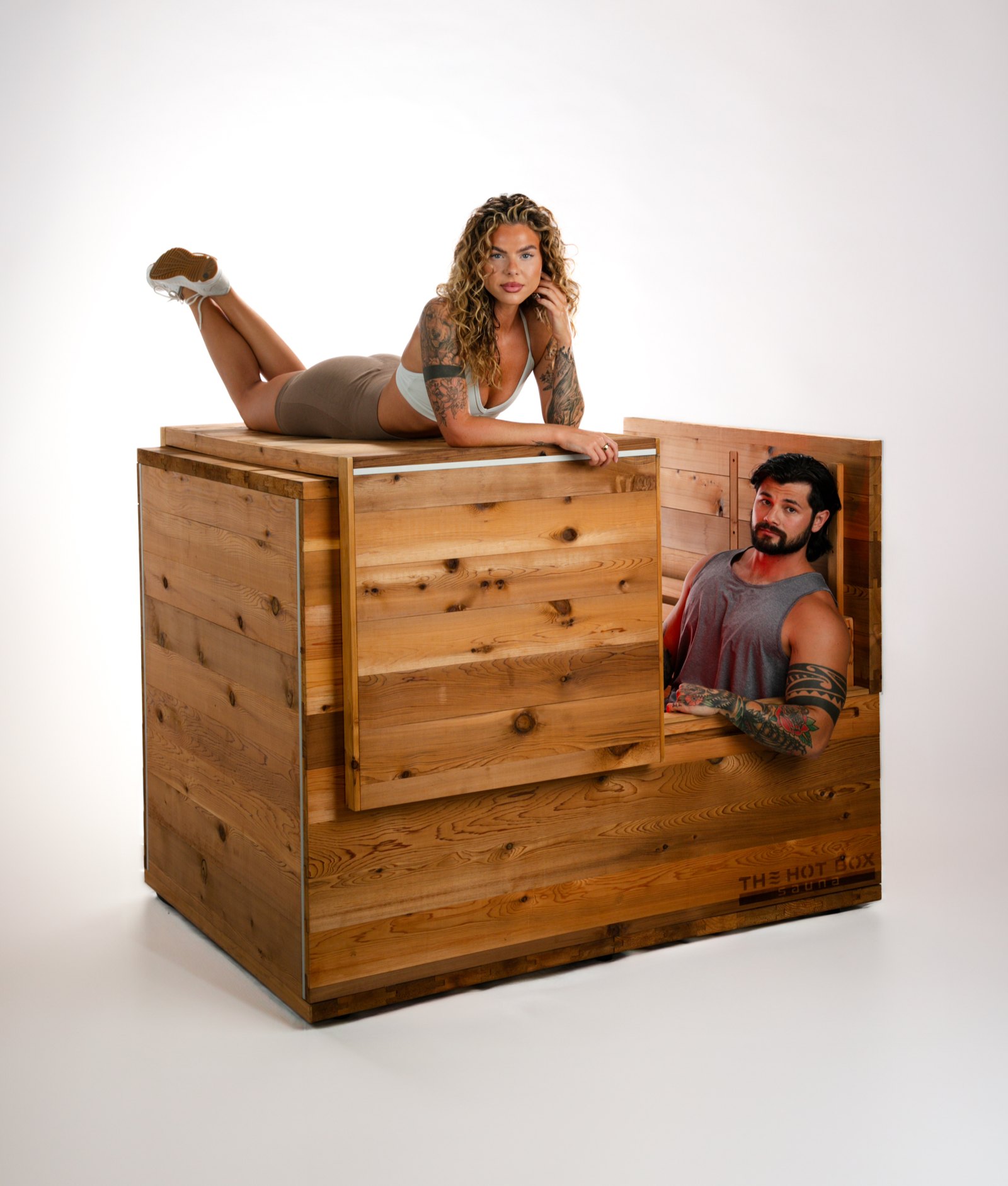 Man sitting inside The Hot Box Sauna with the lid open while a woman lies on top