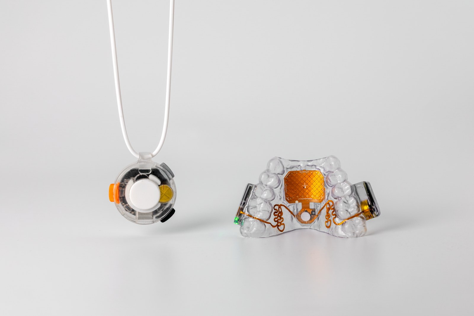 MouthPad shown next to Augmental's VOX microphone pendant
