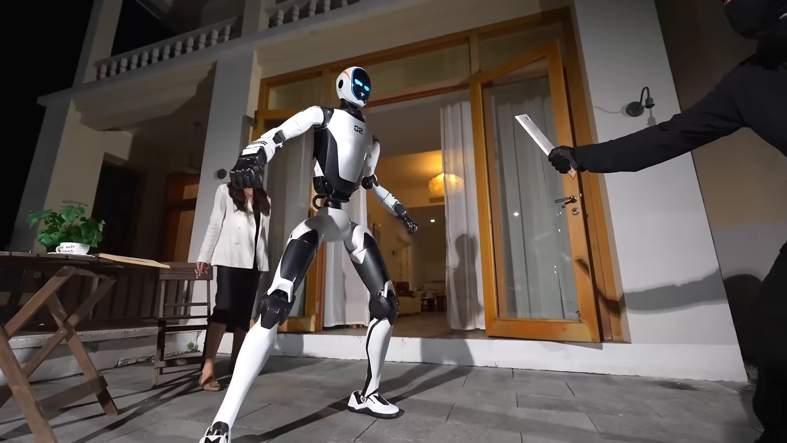 Unitree H2-X robot standing guard between a woman and an intruder holding a knife in a staged scene