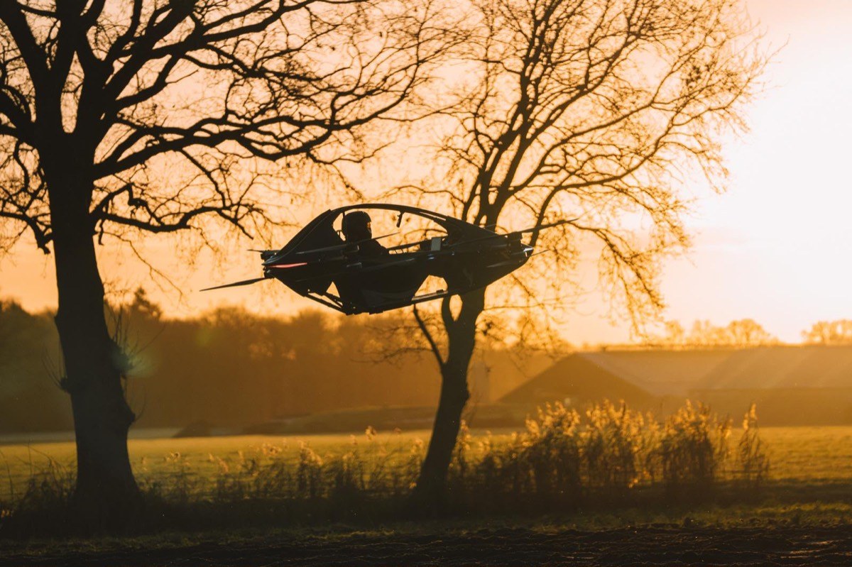 YIVTOL S-Zero hovering between bare trees in silhouette at sunset over a field